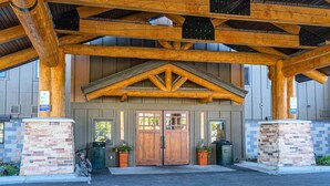 A building with a wooden facade, a brick entrance, and a metal roof structure. - 3BR in resort near West Entrance, Pool, Hot Tub. (West Yellowstone)