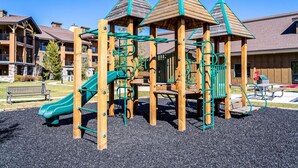 A playground with climbing structures and a slide, surrounded by a gravel area. - 3BR in resort near West Entrance, Pool, Hot Tub. (West Yellowstone)