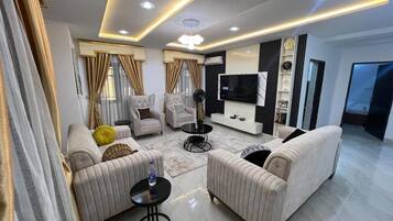 A modern living room with a sofa set, a coffee table, a TV, and a fireplace.
