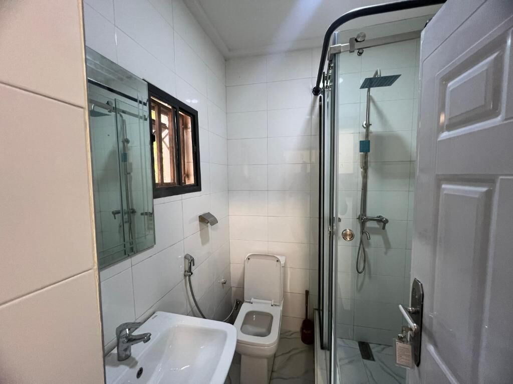 A bathroom with a glass-enclosed shower, a sink, and a toilet.