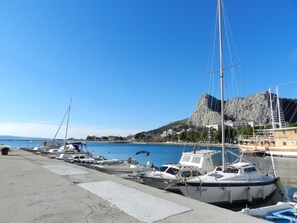 A marina with boats docked, a rocky cliff in the background, and buildings along the waterfront. - Apartment Adriatic Panorama View (Omis)