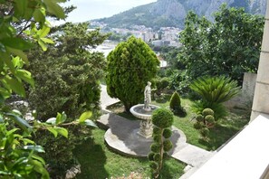 A landscaped garden with a fountain, trimmed bushes, and a statue. - Apartment Adriatic Panorama View (Omis)