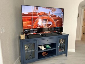 A television on a dark blue cabinet with glass doors, displaying a music video. - Casa Blanca - Villa D18 (Sarasota)