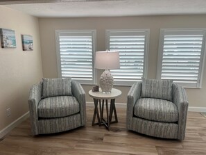 A room with two armchairs, a small table with a lamp, and three windows with blinds. - D16 - Turn Moments into Memories on Siesta Key (Sarasota)