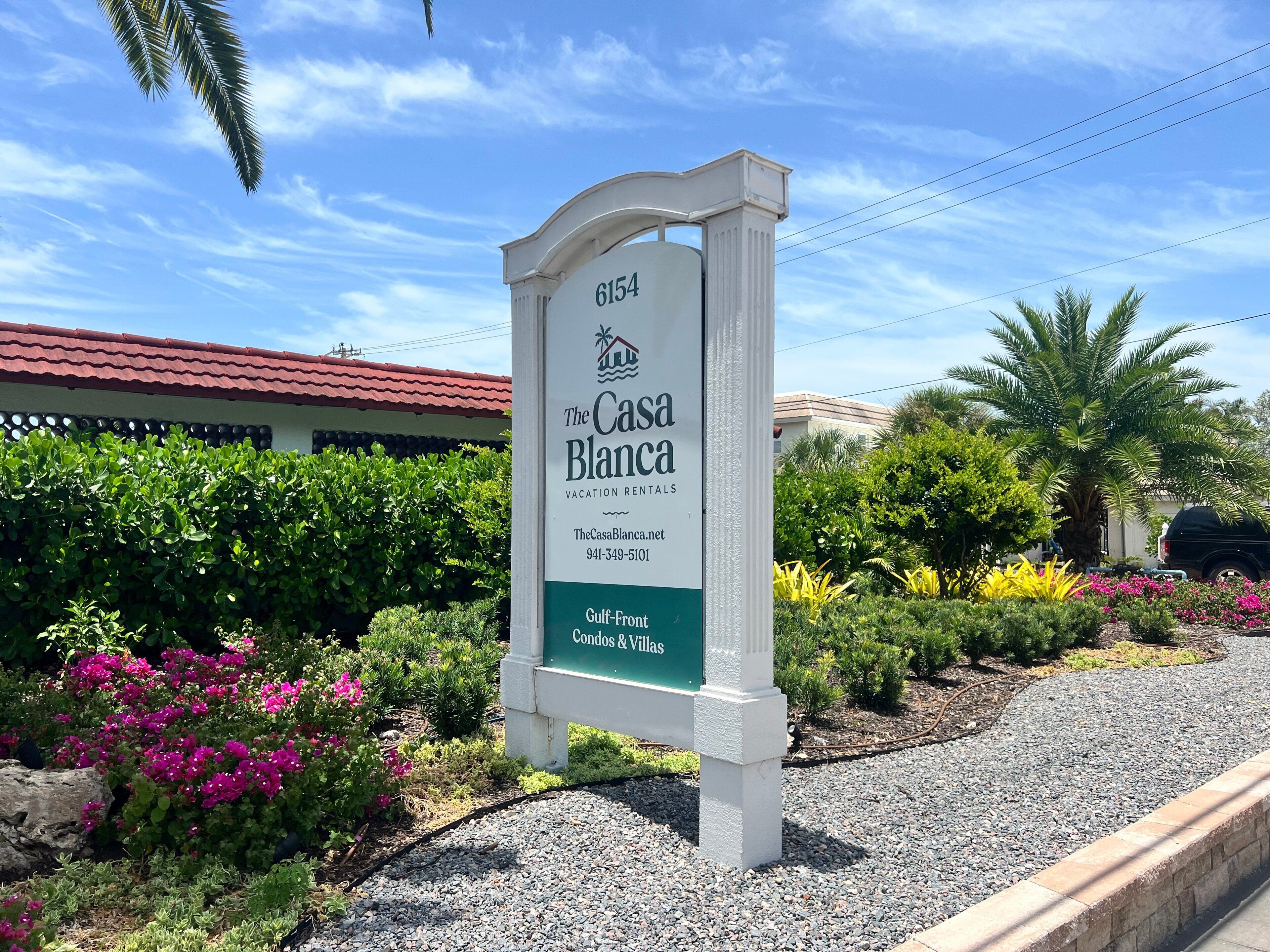 A sign for The Casa Blanca, a vacation rental property, with a contact number and website listed.