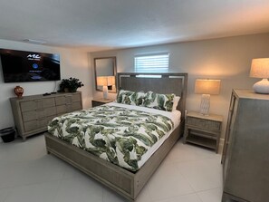 Ein modernes Schlafzimmer mit einem Bett, Nachttischen, einem Fernseher und einem Spiegel.