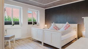 Ein Schlafzimmer mit Bett, Fenster mit Ausblick, Nachttisch und Stuhl.