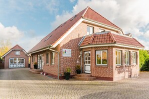 Un bâtiment en briques surmonté d’un toit de tuiles rouges, avec un garage et une enseigne indiquant qu’il s’agit d’une école maternelle.