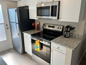 A compact kitchen with a refrigerator, microwave, stove, and oven. - Casa Blanca - Villa D05 (Sarasota)