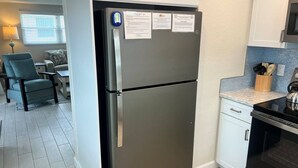 A modern kitchen with a stainless steel refrigerator, a built-in oven, and a countertop with a knife block. - Casa Blanca - Villa D03 (Sarasota)