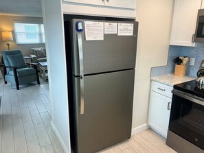 Eine moderne Küche mit einem Edelstahl-Kühlschrank, einem Einbauofen und einer Arbeitsplatte mit Messerblock.
