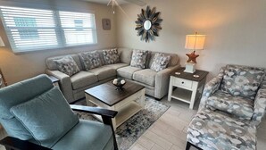 A living room with a sectional sofa, a single armchair, a coffee table, a side table with a lamp, and a ceiling fan. - Casa Blanca - Villa D03 (Sarasota)