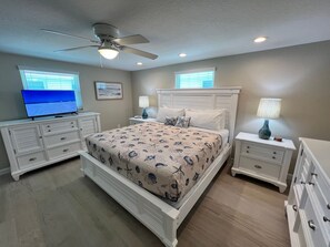 A bedroom with a bed, two nightstands, a ceiling fan, a television, and a window with blinds. - Casa Blanca  -Villa C15 (Sarasota)