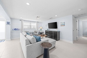 A modern living room with a sectional sofa, a flat-screen TV, and a dining area. - Casa Blanca - Villa C09 (Sarasota)