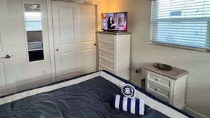 A bedroom with a bed, a television on a dresser, a ceiling fan, and a window with blinds. - Casa Blanca - Villa C08 (Sarasota)