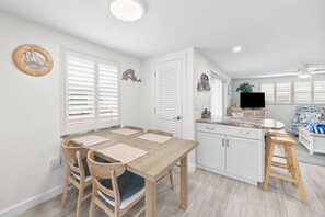A compact kitchen with white cabinets, a dining table with chairs, and a small island with a sink. - Casa Blanca - Villa C08 (Sarasota)