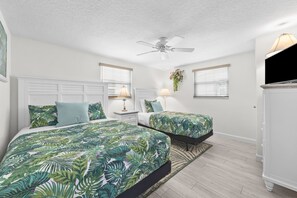 A bedroom with two beds, a ceiling fan, a TV, and a plant. - Casa Blanca - Villa C08 (Sarasota)