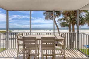 Ein überdachter Außenbereich mit Blick auf den Strand und Palmen.