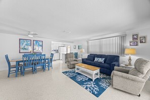 Un salon moderne avec un canapé bleu, une table basse et un coin repas avec des chaises bleues.