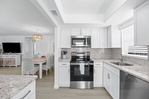 A modern kitchen with white cabinetry, a stainless steel oven, a microwave, and a granite countertop. - Casa Blanca Villa A11 (Sarasota)