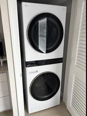 A compact, white stacked washer and dryer unit in a narrow hallway. - Casa Blanca Villa A11 (Sarasota)