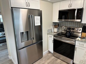 A kitchen with stainless steel appliances, including a refrigerator, microwave, stove, and oven. - A12 - Stay. Relax. Repeat. (Sarasota)