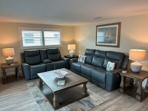 A living room with two black leather sofas, a wooden coffee table, and two side tables with lamps. - Casa Blanca - Villa A12 (Sarasota)