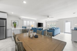 A spacious living area with a dining table, blue sofas, and a kitchen in the background. - Casa Blanca A18- Siesta Key Is Calling (Sarasota)