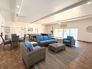 A spacious indoor area with wicker furniture, a pool table, and a ceiling fan. - Casa Blanca - Villa B01 (Sarasota)