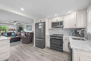 A modern kitchen with white cabinetry, a stainless steel refrigerator, a microwave, and a gas stove. - Casa Blanca - Villa B01 (Sarasota)
