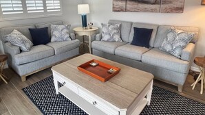 A living room with two grey sofas, a coffee table, a lamp, and a painting on the wall. - Casa Blanca - Villa B04 (Sarasota)