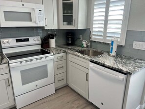 A modern kitchen with white cabinetry, a built-in microwave, a stove, and a dishwasher. - Casa Blanca - Villa B05 (Sarasota)