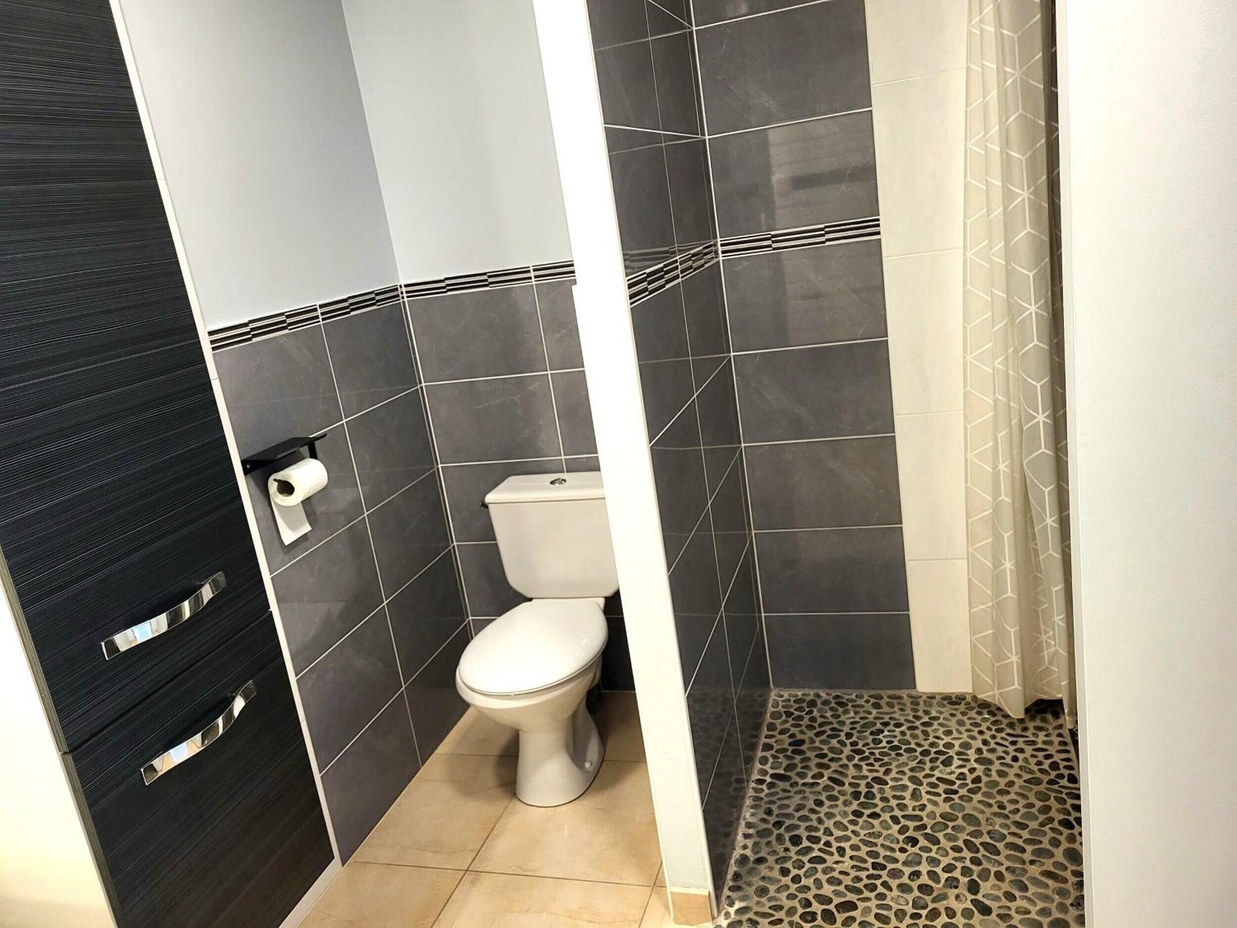 A bathroom with a toilet, a towel rack, and a shower area.