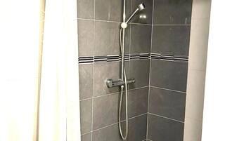 A shower with a curved hose, a handheld showerhead, and a control panel.
