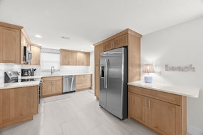 Une cuisine moderne avec des meubles en bois, des appareils en acier inoxydable et un plan de travail blanc.