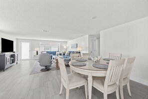 Un salon moderne avec un coin repas, comprenant un téléviseur, un canapé et une table à manger avec des chaises.