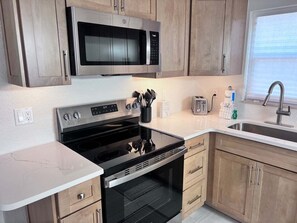 A modern kitchen with stainless steel appliances, wooden cabinets, a built-in oven, and a sink. - Casa Blanca - Villa B06 (Sarasota)