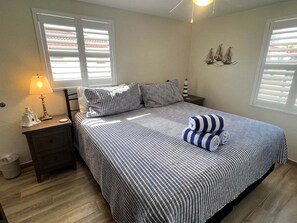 Une chambre à coucher comprenant un lit, des tables de chevet, une lampe et un décor mural représentant un navire.