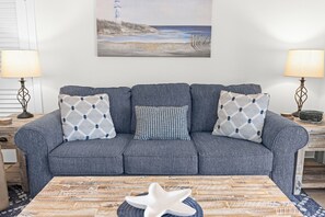 A living room with a gray sofa, patterned throw pillows, a wooden coffee table, and a starfish decoration. - Casa Blanca - Villa B10 (Sarasota)