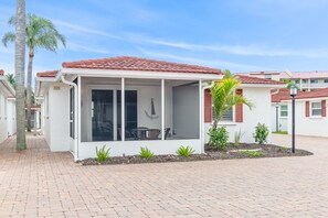 A covered outdoor seating area with a patio, a palm tree, and a small garden. - Casa Blanca - Villa B10 (Sarasota)