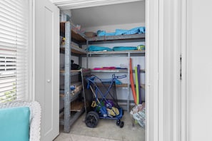 A storage area with metal shelving units, a blue cart, and a white door. - Casa Blanca - Villa B11 (Sarasota)