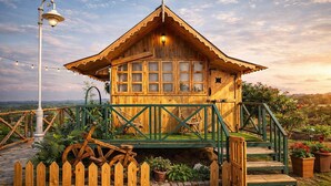 A wooden cabin with a balcony, a wooden fence, and a lamp post. - Sierra Vista Resort (Talegaon)