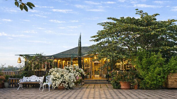 A building with a tiled entrance, a bench, and potted plants. - Sierra Vista Resort (Talegaon)