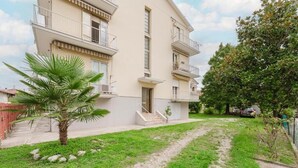 Un edificio residenziale a più piani con balconi, un vialetto lastricato e una piccola palma.