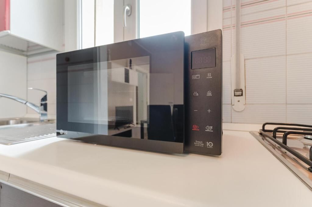 Une cuisine moderne équipée d’un four à micro-ondes noir, d’un évier en acier inoxydable et d’une cuisinière à gaz.
