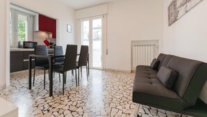 Un ambiente compatto con angolo ristoro, angolo cottura e divano.