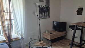 Un soggiorno moderno con televisione, mobili in legno, un tavolo in vetro e una lampada.