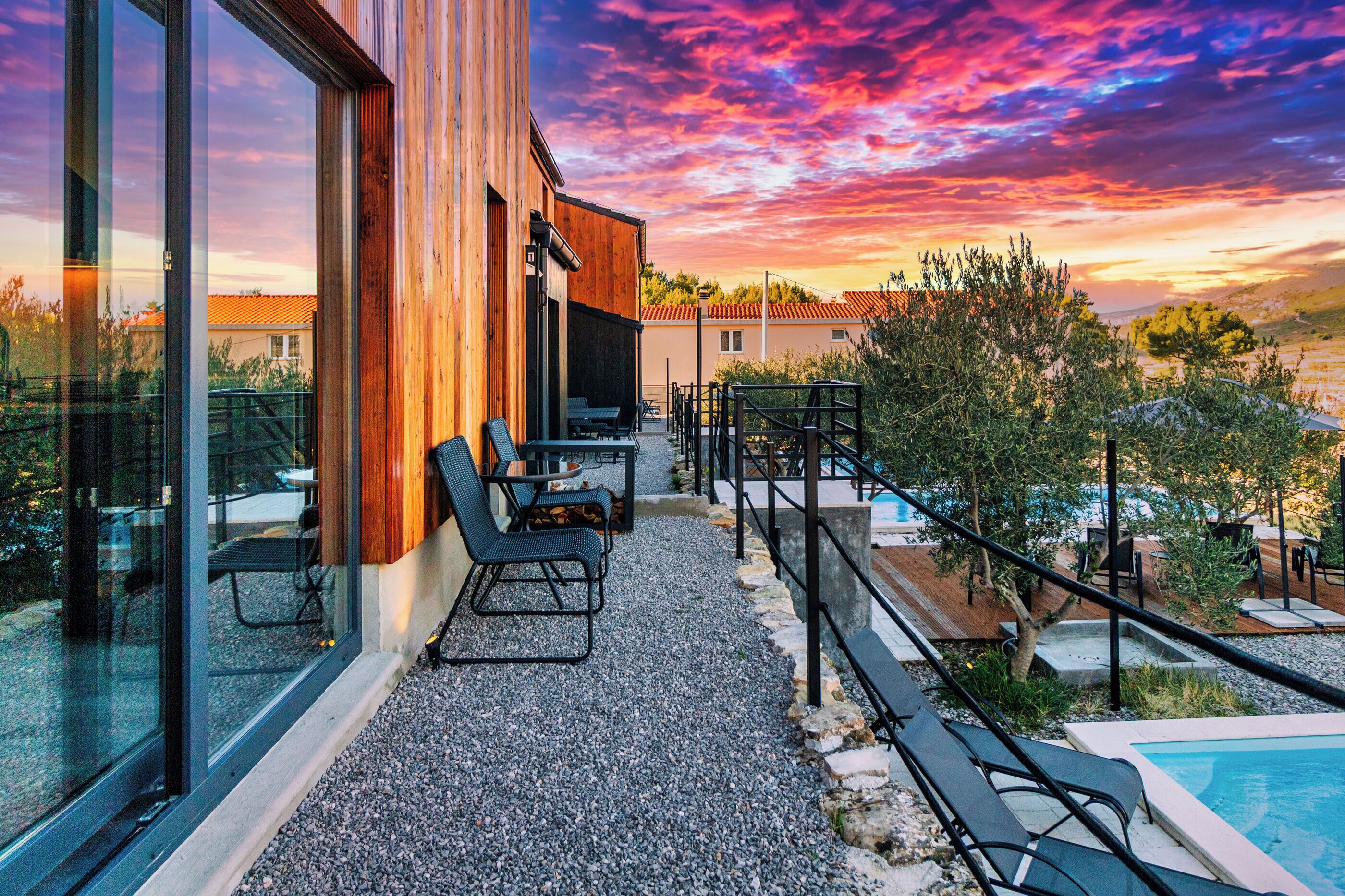 Un patio moderno al aire libre con piscina, zona de estar y vistas del paisaje circundante.