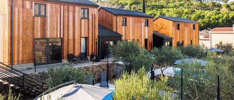 A modern wooden building with multiple rooms, outdoor seating, and a pool area.