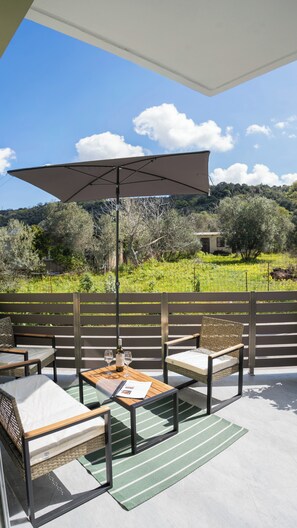 Eine Terrasse im Freien mit Tisch, Stühlen und einem großen Sonnenschirm.